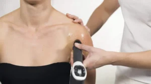 Fisioterapeuta aplicando ondas de choque en tendinitis de bíceps de una paciente en Málaga